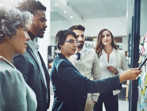 Shot of a group of focused businesspeople having a discussion while making use of a glass white board to go through notes