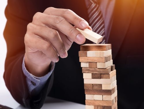 Planning, risk and strategy in business concept, businessman gambling placing wooden block on a tower.